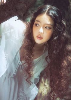 a woman with long hair sitting on a tree branch