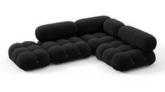 a large black couch with multiple pillows on the bottom and back ends, sitting in front of a white background