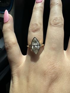 a woman's hand with a ring on it and a car steering wheel in the background