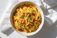 a white bowl filled with macaroni and cheese on top of a white cloth