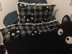 two pillows with black cats on them sitting next to a teddy bear and stuffed animal