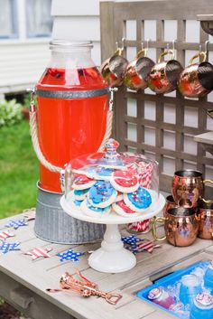 a table topped with an ice bucket filled with red, white and blue cookies next to other items