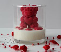 a teddy bear in a glass vase with candles