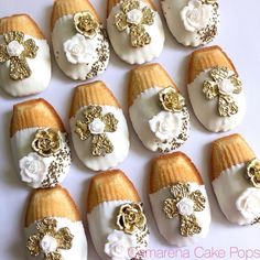 there are many decorated cakes with gold and white flowers on them, all arranged in rows