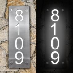 two metal signs with numbers on them are next to each other in front of a stone wall