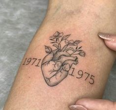 a woman's arm with a heart and flowers tattoo on it