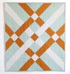 an orange and blue quilt hanging on the wall