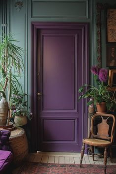 a purple door with potted plants in the corner and a chair next to it