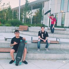 three young men sitting on steps with skateboards in their hands and one holding a skateboard