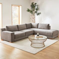 a living room with a large sectional couch and coffee table in the corner, along with a potted plant