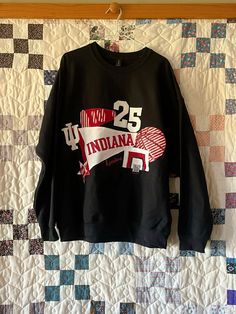 a black sweatshirt with the number twenty five on it hanging from a quilted wall