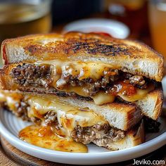 a grilled cheeseburger is cut in half and served on a white plate