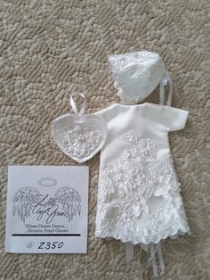 a white dress with angel wings on it next to a tag and some other items