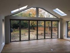 an empty room with large windows and wooden floors