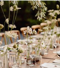 the table is set with white flowers and place settings for dinner guests to sit at