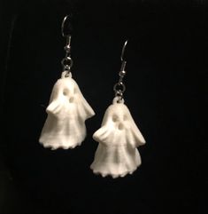 a pair of earrings with white flowers hanging from it's ear hooks on a black background