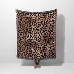 a woman standing in front of a leopard print blanket with tassels on it