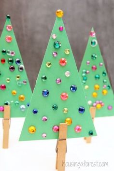 three christmas trees made out of popsicle sticks and colored jewels on them, sitting next to each other