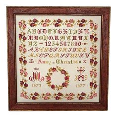 a cross stitch sample in a wooden frame with flowers and numbers on the bottom half