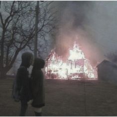 two people standing in front of a fire that has been set alighted from the ground