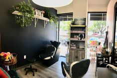 a salon with black walls and lots of plants on the shelves in front of it