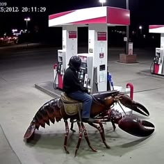 a man riding on the back of a lobster at a gas station