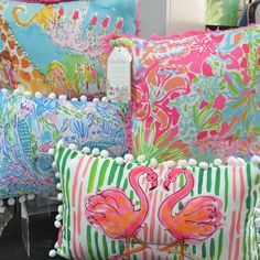 colorful pillows with pom poms and flamingos are on display at the store