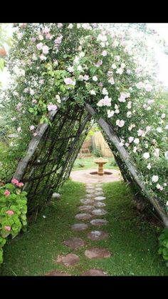 an arch made out of branches with flowers on the side and a fire hydrant in the middle