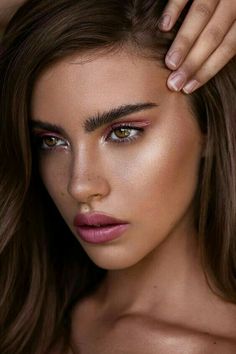 a woman with long brown hair and pink eyeshadow is posing for the camera