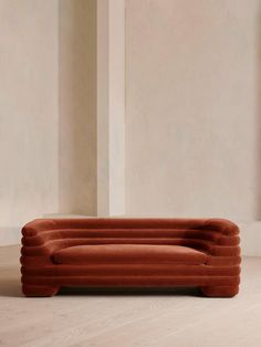 an orange couch sitting on top of a hard wood floor next to a white wall