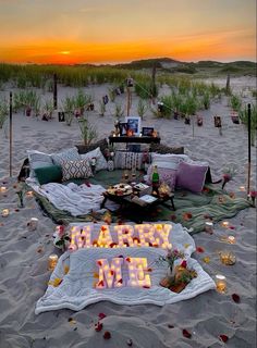 a happy new year sign on the beach with candles and flowers in front of it