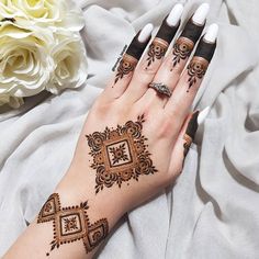 a woman's hand with henna tattoos on it and flowers in the background