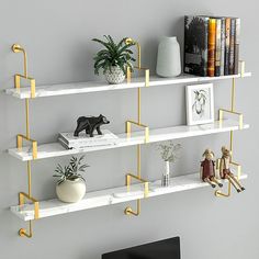 three white shelves with gold handles and some books on them, along with a television