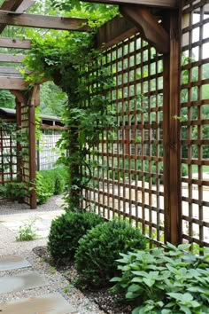 a wooden pergoline surrounded by greenery and stone walkway leading to an open area