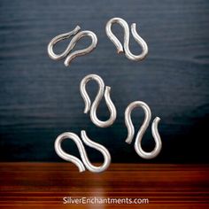 three silver metal hooks on top of a wooden table