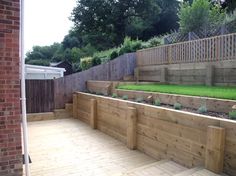 a wooden deck with raised planters in the middle and grass growing on it's sides