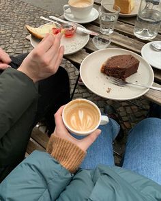 two people sitting at a table with plates of food and drinks