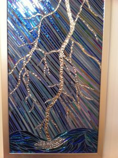 a decorative glass panel with a tree in the center and blue water behind it on a white wall