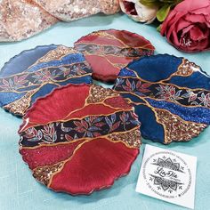 four decorative plates sitting on top of a table next to some flowers and a card