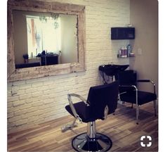 a salon chair sitting in front of a brick wall with a mirror on the wall