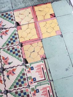 colorful tiles on the ground in front of a building with peeling paint and chipping