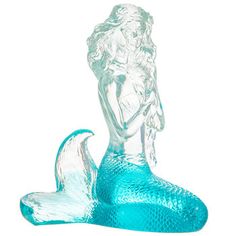 a glass mermaid figurine sitting on the ground