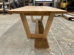 a wooden table sitting on top of a floor in a room filled with woodworking equipment