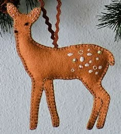 a wooden deer ornament hanging from a pine tree with a card in the background