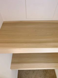 a wooden shelf sitting on top of a carpeted floor next to a white wall