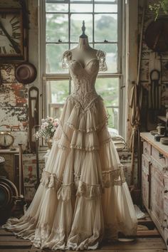 a dress on display in front of a window with an old fashioned clock behind it