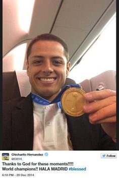 a man holding up a gold medal in his right hand and smiling at the camera