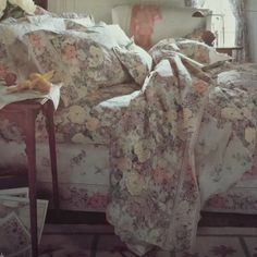 an old photo of a bed covered with floral bedspreads and blankets, next to a window