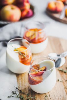 two glasses filled with liquid sitting on top of a wooden cutting board next to apples