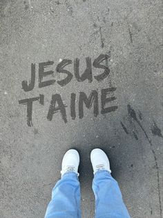 someone is standing on the pavement with their feet up and writing jesus tame in black ink